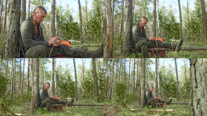 男性荒野生存专家坐在森林的树干上编织干草