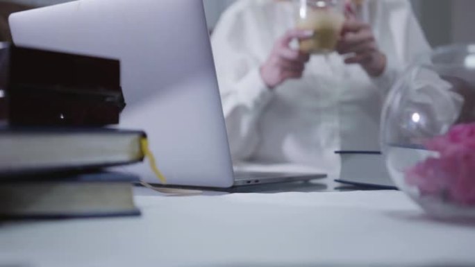 女性高加索成熟手的特写镜头，法国美甲拿着咖啡杯，上网冲浪。高级聪明女人在家使用笔记本电脑。爱好，消遣