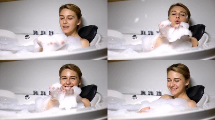 滑稽的女性躺在浴缸里，把泡沫吹到相机里，孩子气的心情