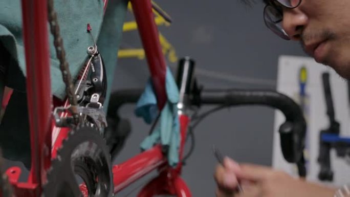 4k慢动作亚洲男子戴眼镜他是一家自行车店的老板。是一家小企业，他正在修理自行车并旋转车轮。检查条件，