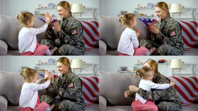 快乐的美国女兵和孩子在沙发上玩手，孩子拥抱着妈妈