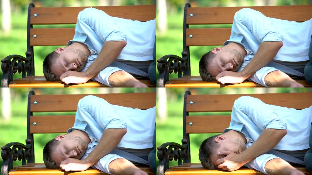 年轻人早上醒来，在不眠之夜后躺在公园的长凳上