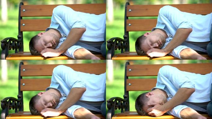 年轻人早上醒来，在不眠之夜后躺在公园的长凳上