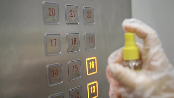 人们戴着手套在公寓清洁新型冠状病毒肺炎中使用喷雾酒精作为电梯按钮在日常病毒