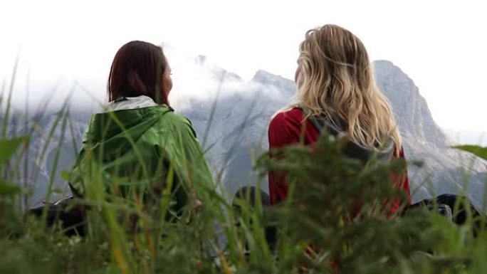阴天，两名女性徒步旅行者在山脊山顶小径上放松