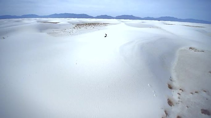 年轻的高加索人，带着大背包的游客，在沙质沙漠中的沙丘顶上休息，然后开始行走。美国新墨西哥州白沙国家纪