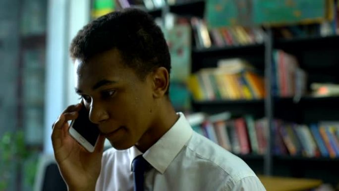 聪明的男性高中生在学院图书馆讲智能手机，交流
