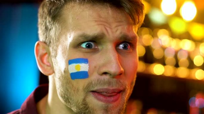 阿根廷男球迷对国家足球队的失利感到不满，脸颊上的旗帜