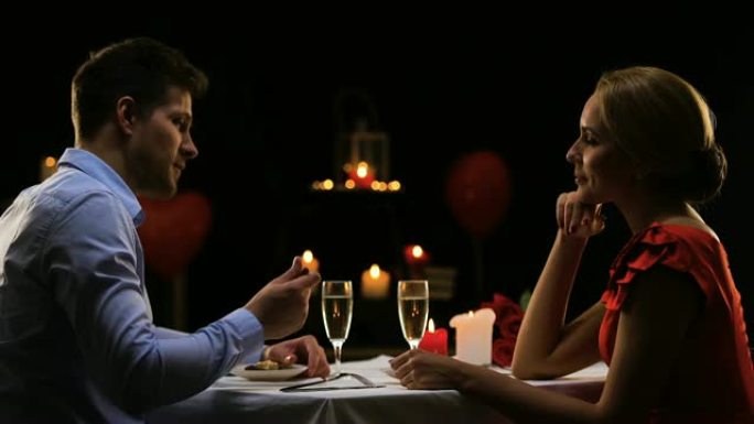 英俊的男人喂养漂亮的女士，夫妇在餐厅吃浪漫的晚餐