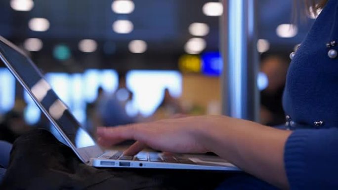 忙碌的女人在机场大厅的笔记本电脑上工作，航班延误，在咖啡馆等候