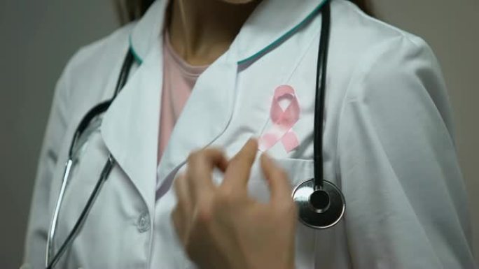 女医生在白色医疗服上系粉红丝带，乳腺癌意识