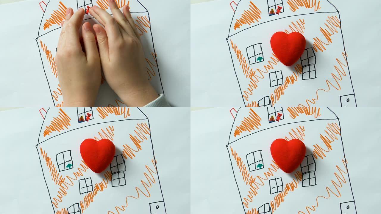 Childs双手将玩具心放在房子的图画上，孤儿梦dream以求的家