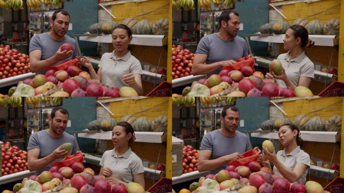 友好的女售货员为男性顾客选择芒果，同时将芒果添加到可重复使用的袋子中
