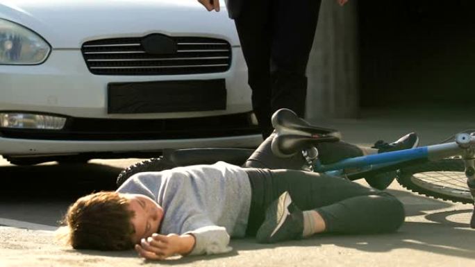 受惊的男司机看着被撞晕的少年躺在街道附近的自行车