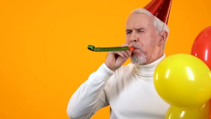 开朗的老人手持彩色气球吹着派对喇叭，活动问候