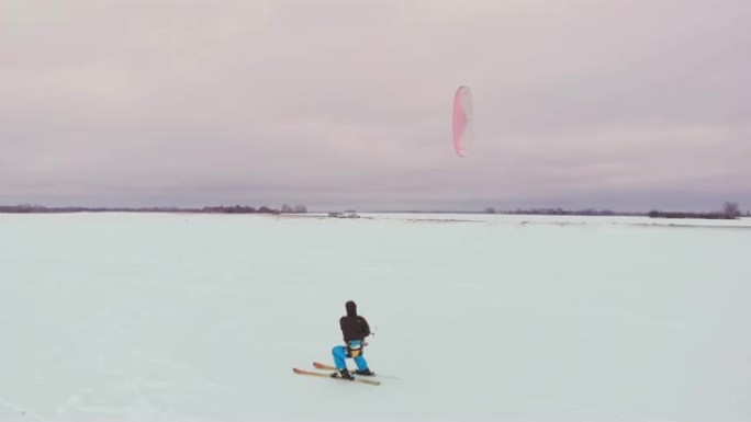 在冬季用滑雪板或滑雪板进行风筝冲浪。在风中在冰上溜冰。美丽的彩色的帆