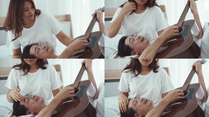 高级夫妇在床上唱歌和弹奏木吉他