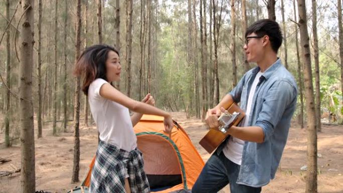 亚洲年轻夫妇弹吉他唱歌享受在松林露营
