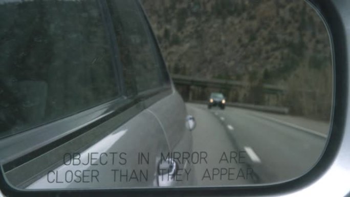 70号州际公路和科罗拉多州的落基山脉在汽车的侧视镜中反射 (镜子中的物体比它们看起来更近)