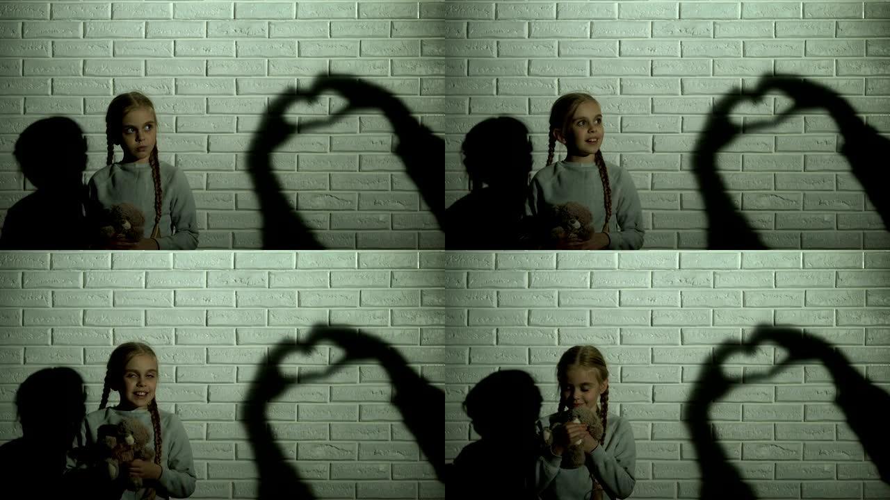 女孩看着墙上的心影，拥抱泰迪熊，希望和善良