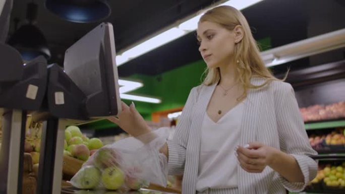 中年妇女在超市称一袋苹果。