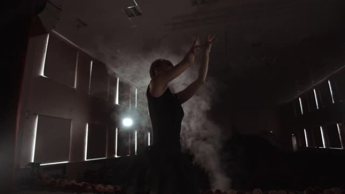 优美的芭蕾舞演员在黑暗中跳舞芭蕾舞元素，背景为灯光和烟雾，慢动作。