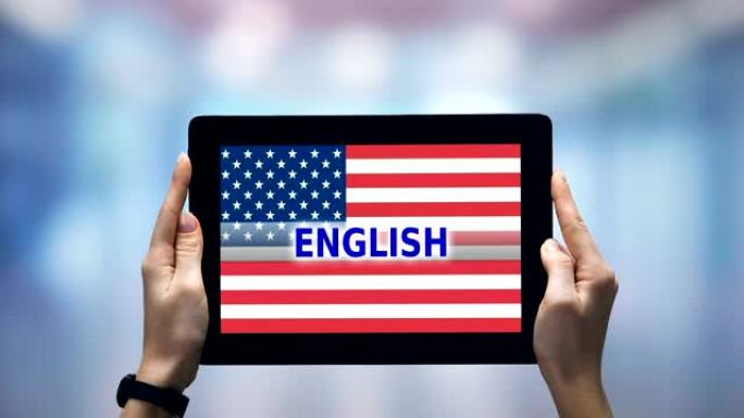 女性手握平板电脑，英语单词反对美国国旗，在线应用