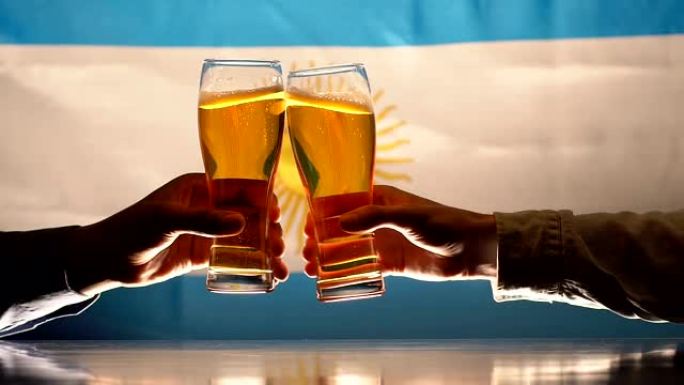球迷叮当作响的啤酒杯，背景上的阿根廷国旗，运动队的支持