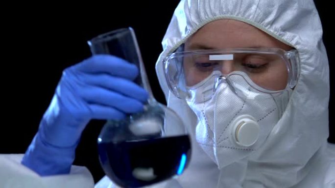 穿着制服的女科学家在化学实验室的烧瓶中显示生物有害液体