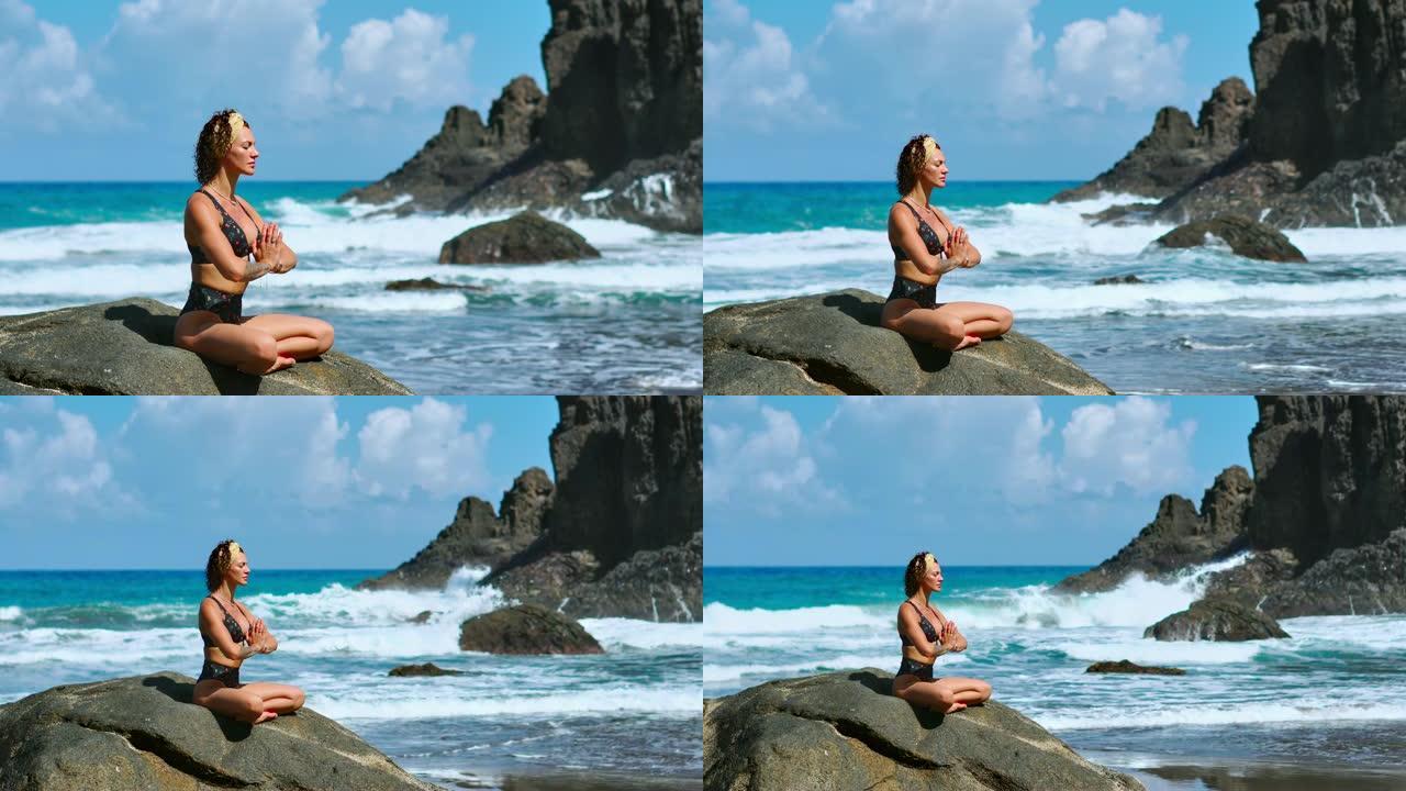 宁静的冥想瑜伽。黑发旅游妇女在风景秀丽的普拉亚达马里尼亚海角上的莲花位置冥想。在加那利群岛的悬崖上冥