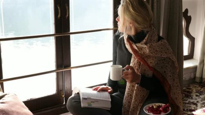 女人用水果和书在窗台上放松