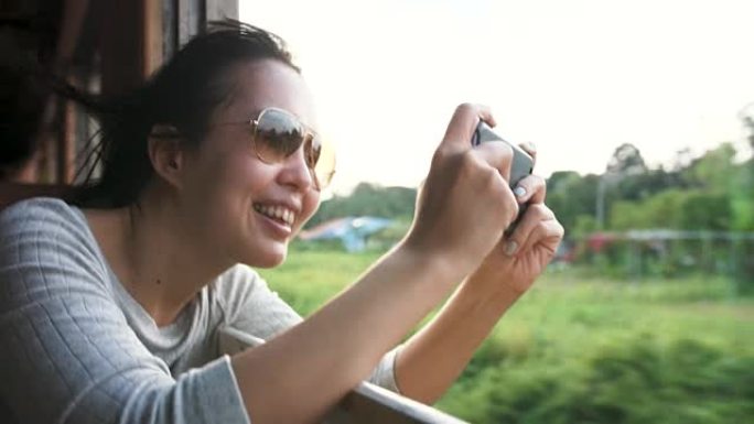 女旅行者在火车上用手机拍照