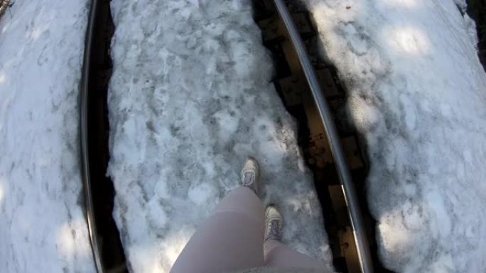 年轻女子沿着白雪皑皑的铁轨行走