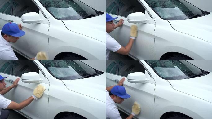 男士在细节商店工人清洁白色汽车时穿着制服和蓝色帽子。