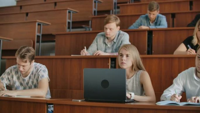 在现代教室里听讲座的同时，一大群多民族学生在笔记本电脑上工作。聪明的年轻人在大学学习