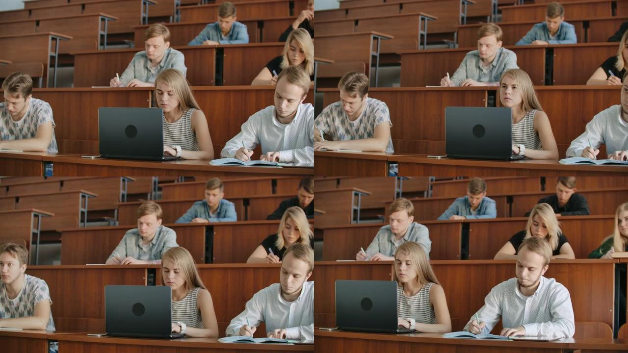 在现代教室里听讲座的同时，一大群多民族学生在笔记本电脑上工作。聪明的年轻人在大学学习