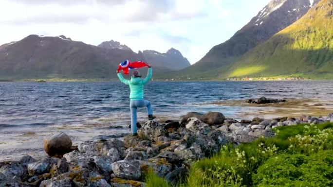 在大自然的背景下挥舞着挪威国旗的女人