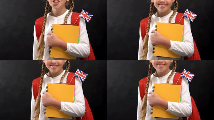 开朗的女孩，书本和英国国旗在镜头前微笑，学习语言