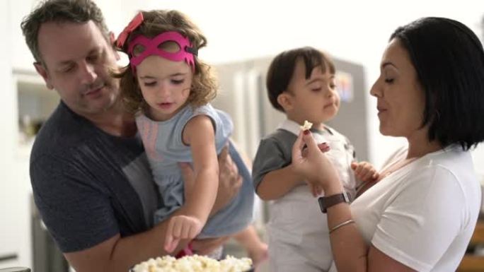 父母和双胞胎兄弟姐妹 (唐氏综合症儿子和女儿) 在家吃爆米花