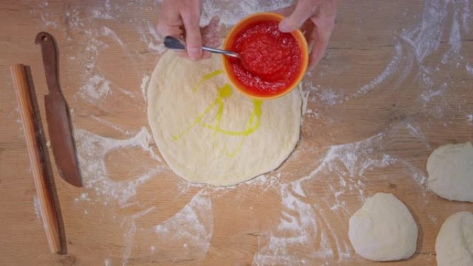 SLO MO LD人将番茄酱放在比萨饼面团上