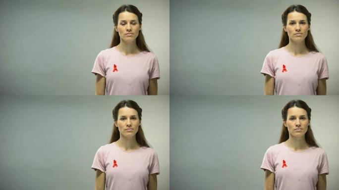 一名身穿红丝带衬衫的年轻女子在镜头前看着，这是艾滋病防治意识的标志