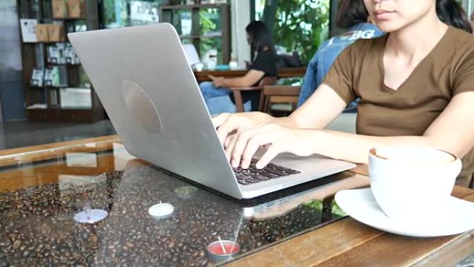 多莉射击动作: 女人在咖啡馆的笔记本电脑键盘上打字