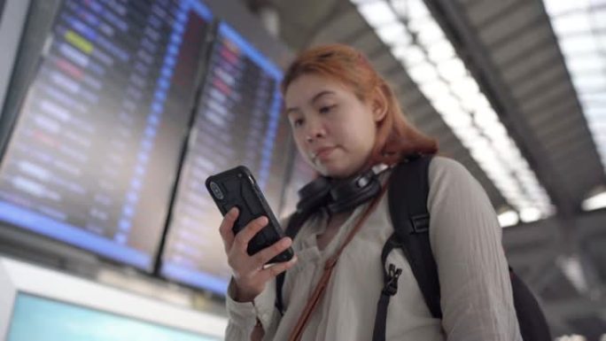 4k镜头女性乘客在机场的航班信息显示系统在线办理登机手续。