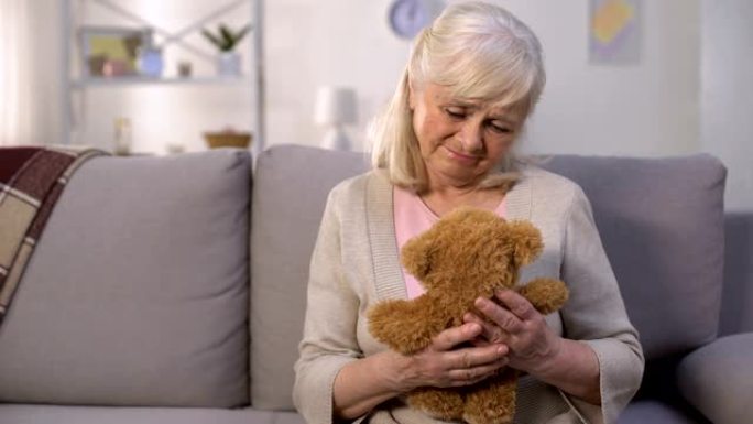 悲伤的老妇人抱着玩具泰迪熊，失踪的孙子，长期分离