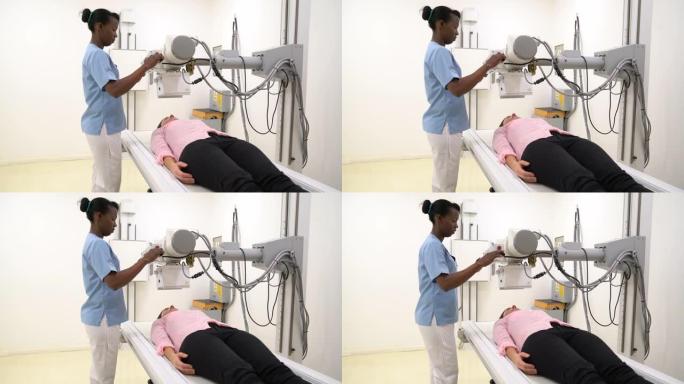 无法识别的女性患者躺下，而女性放射科医生调整机器以进行x射线检查