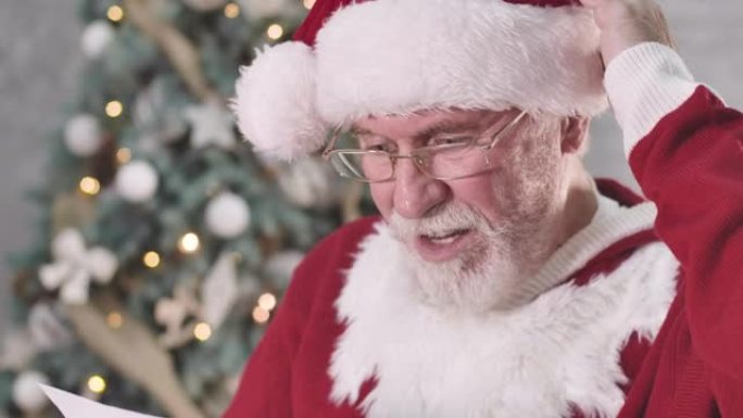 惊讶的圣诞老人读信，看着相机，摇摇头的特写镜头。白胡子的白人老人对现在一无所知。电影院4k ProR