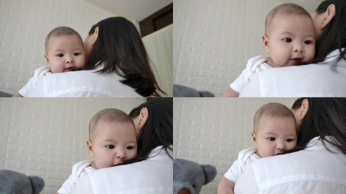 母亲哄婴儿睡在房子的窗户旁