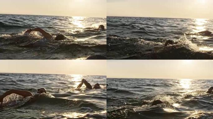 SLO MO男女公开水域游泳运动员在阳光下在海上游泳前爬行