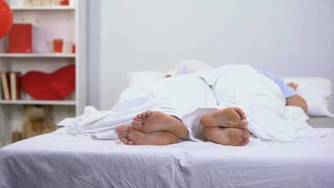 丈夫和妻子睡在床上，在毯子下看到健康的脚，抗真菌药