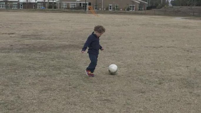 蹒跚学步的孩子独自练习足球